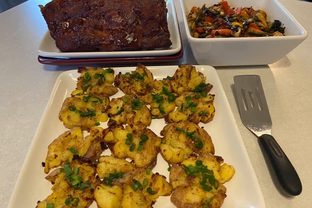 Recipe for Crispy Smashed Potatoes made with small potatoes on dinner table