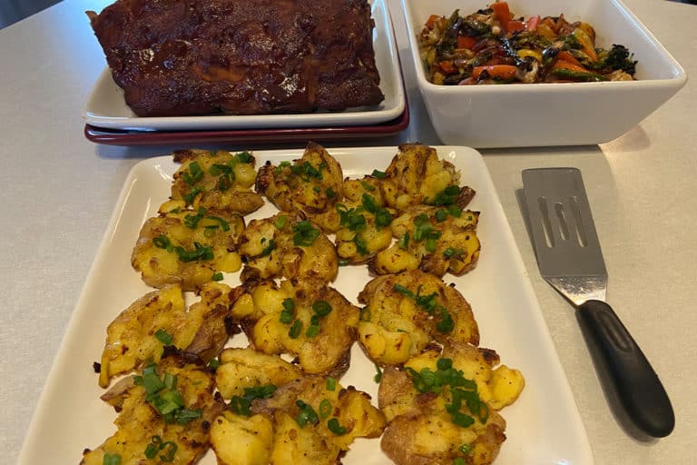 Recipe for Crispy Smashed Potatoes made with small potatoes on dinner table