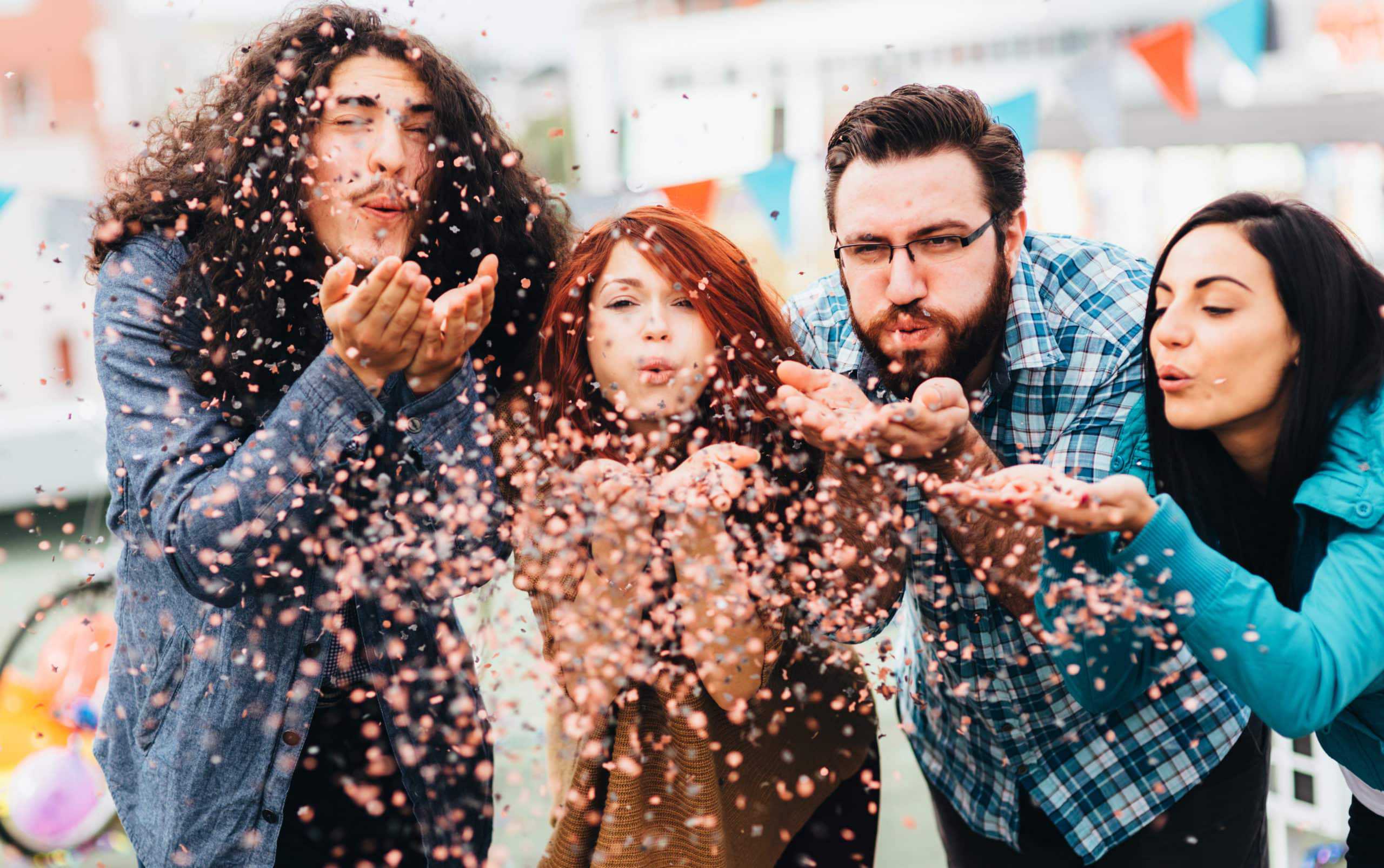 A group of friends blowing conffetti