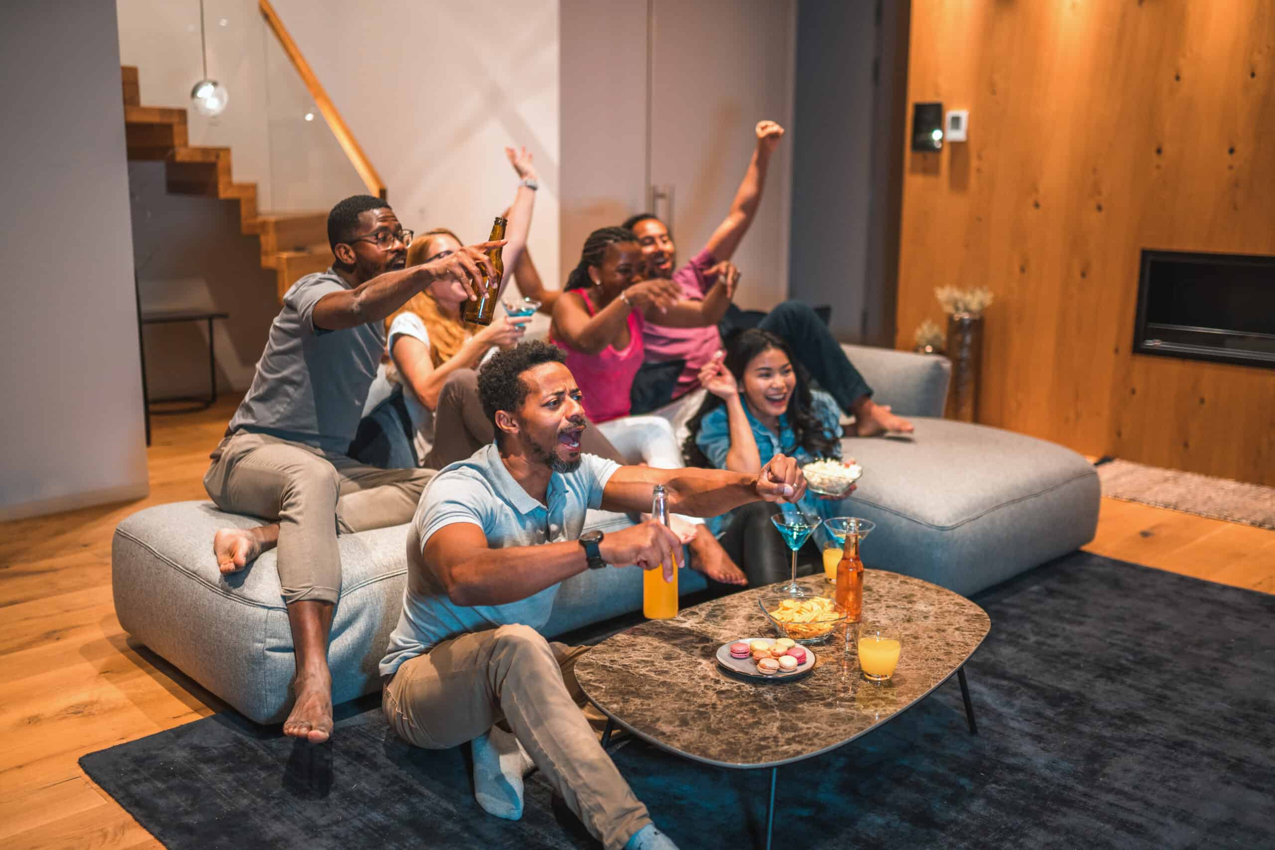 Young people sitting in the living room, watching TV and having fun.