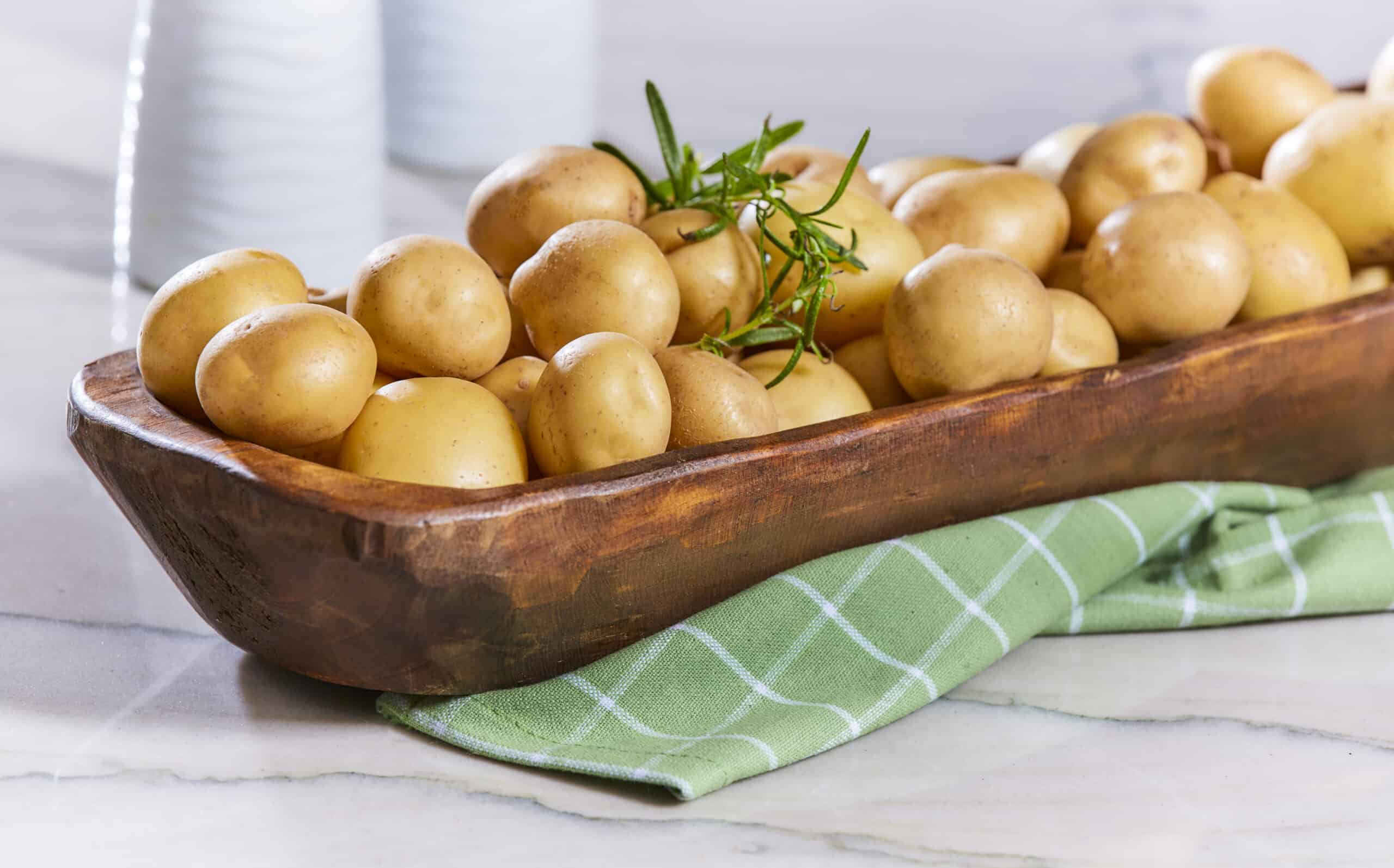 wooden bowl full of Honey Gold® potatoes on countertop.