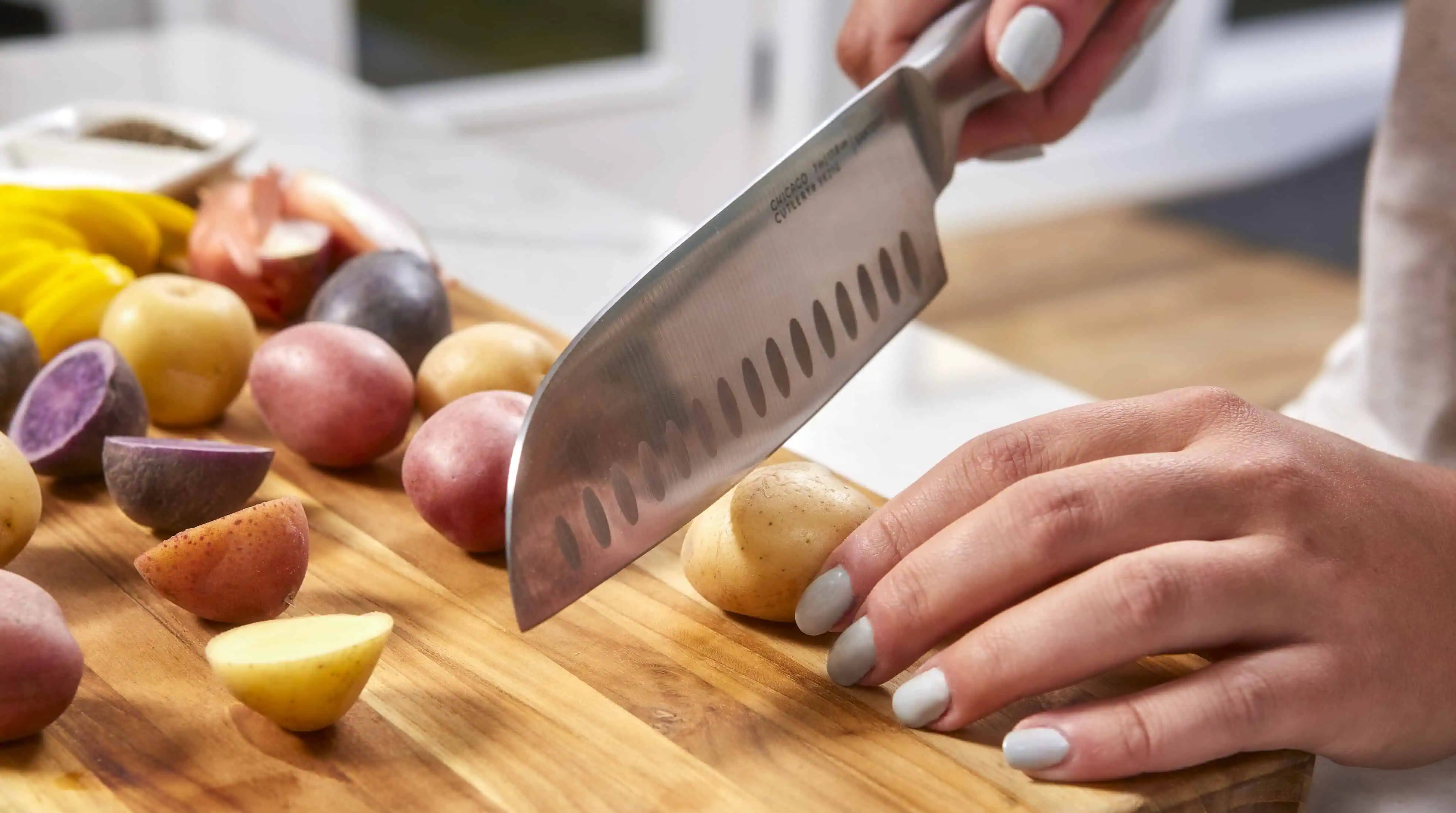 Person slicing potatoes on a wooden board.