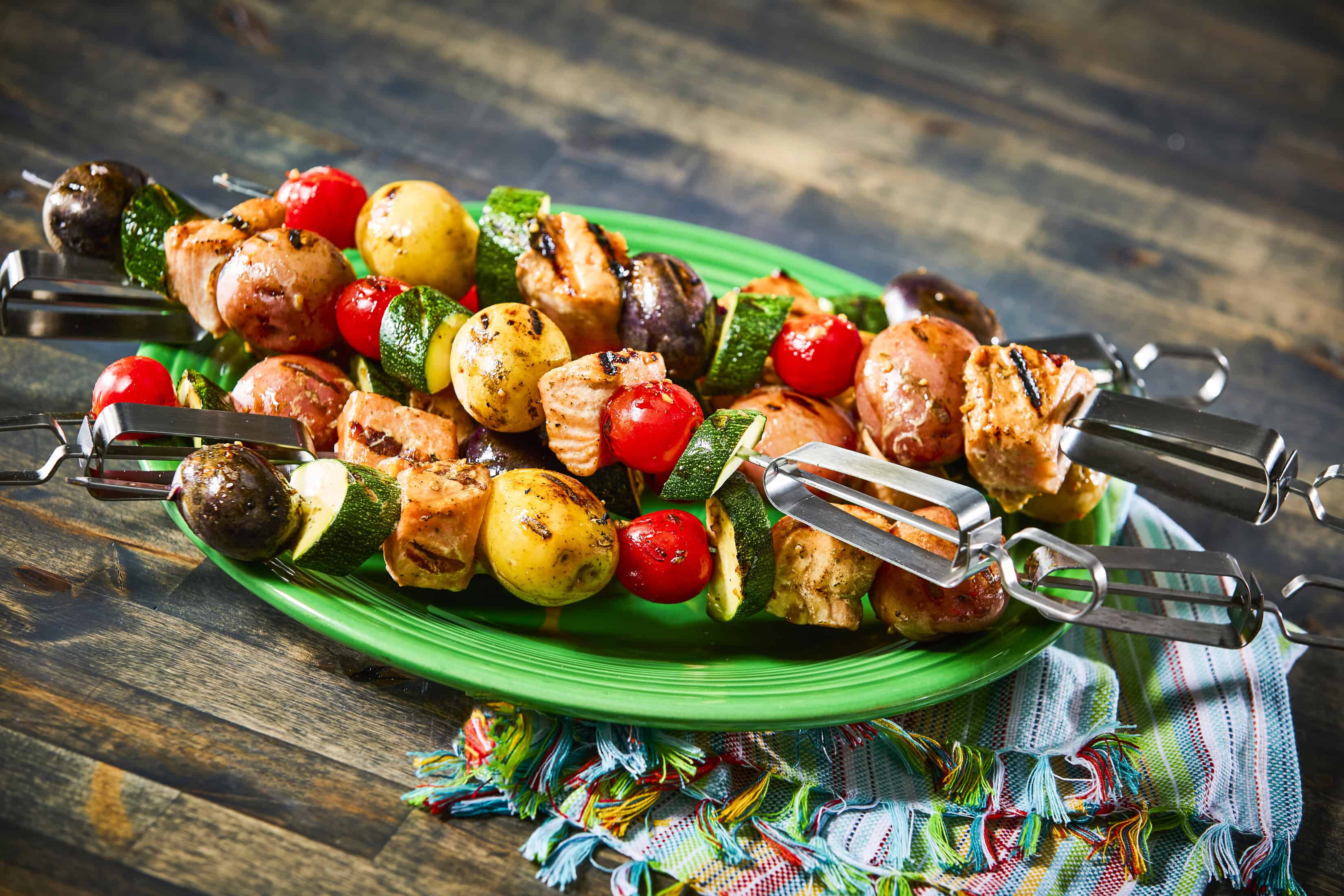 Grilled chicken and vegetable skewers on green plate